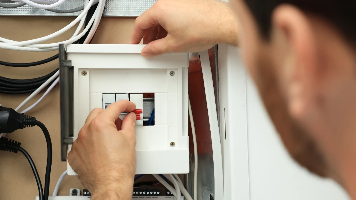 Ev tipi sigorta kutusunun kapağını açıp kaçak akım rölesine dokunan eller